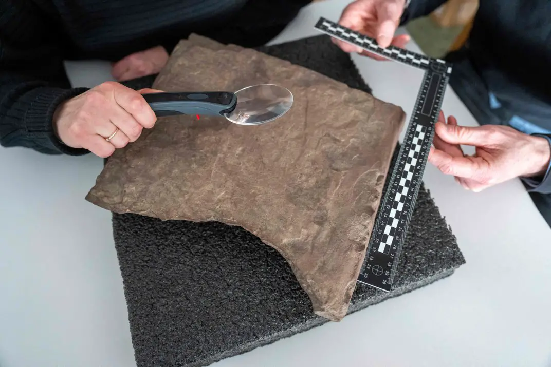 Les chercheurs examinant la pierre runique de 12 pouces sur 12 pouces
