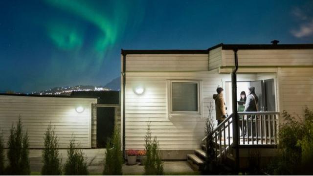 Les Témoins de Jéhovah évangélisent en Norvège. Ils sont à Ranheim et l'aurore boréale est en arrière-plan. Source : jw.org.