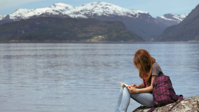 Livres sur la Scandinavie : Les meilleures lectures sur l'Europe du Nord 80 Fille lisant un livre scandinave au bord d'un fjord.