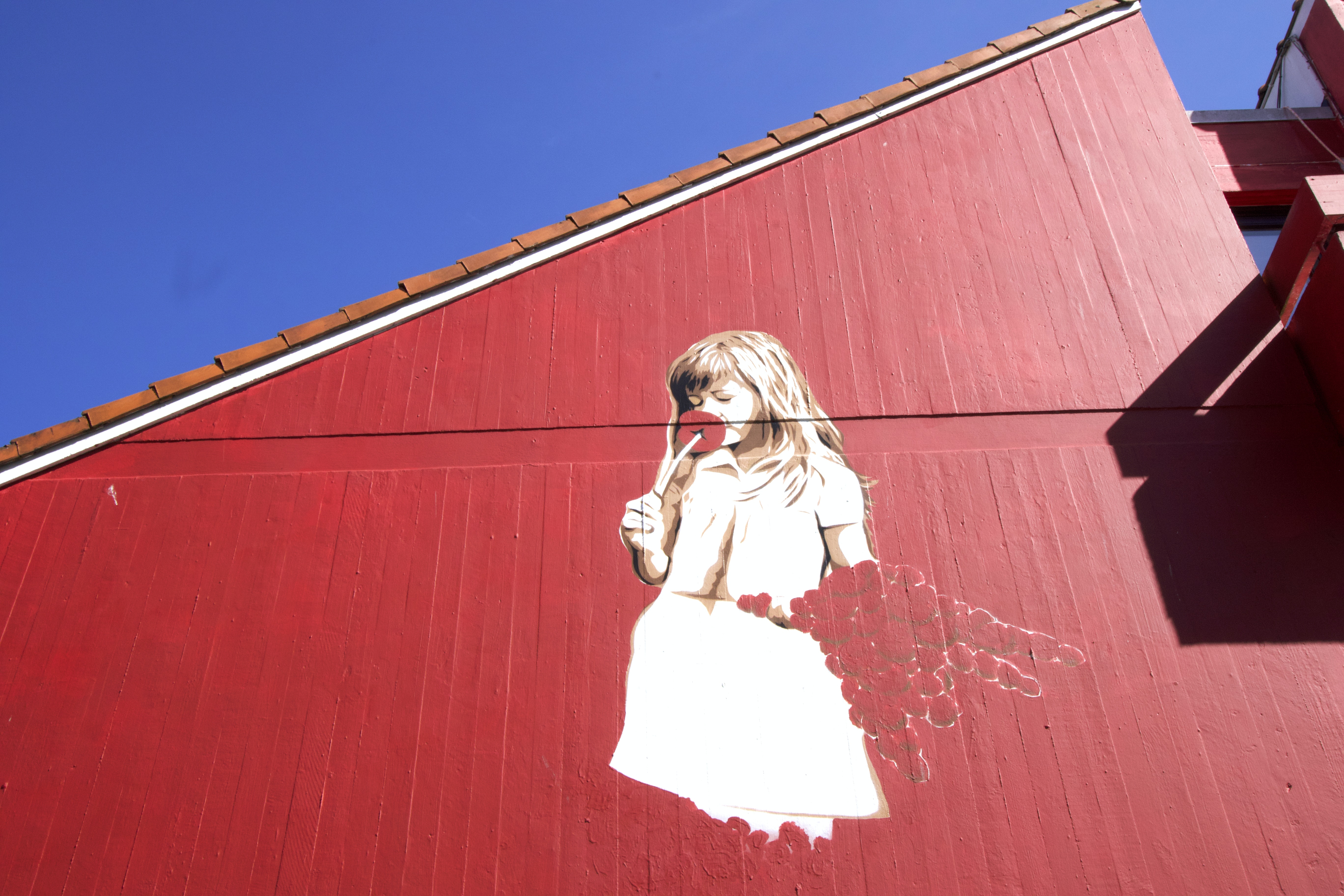Balade à la découverte d'un fjord du sud de la Norvège 15 Peinture murale de Stavanger représentant une jeune fille en robe blanche sur un mur rouge.