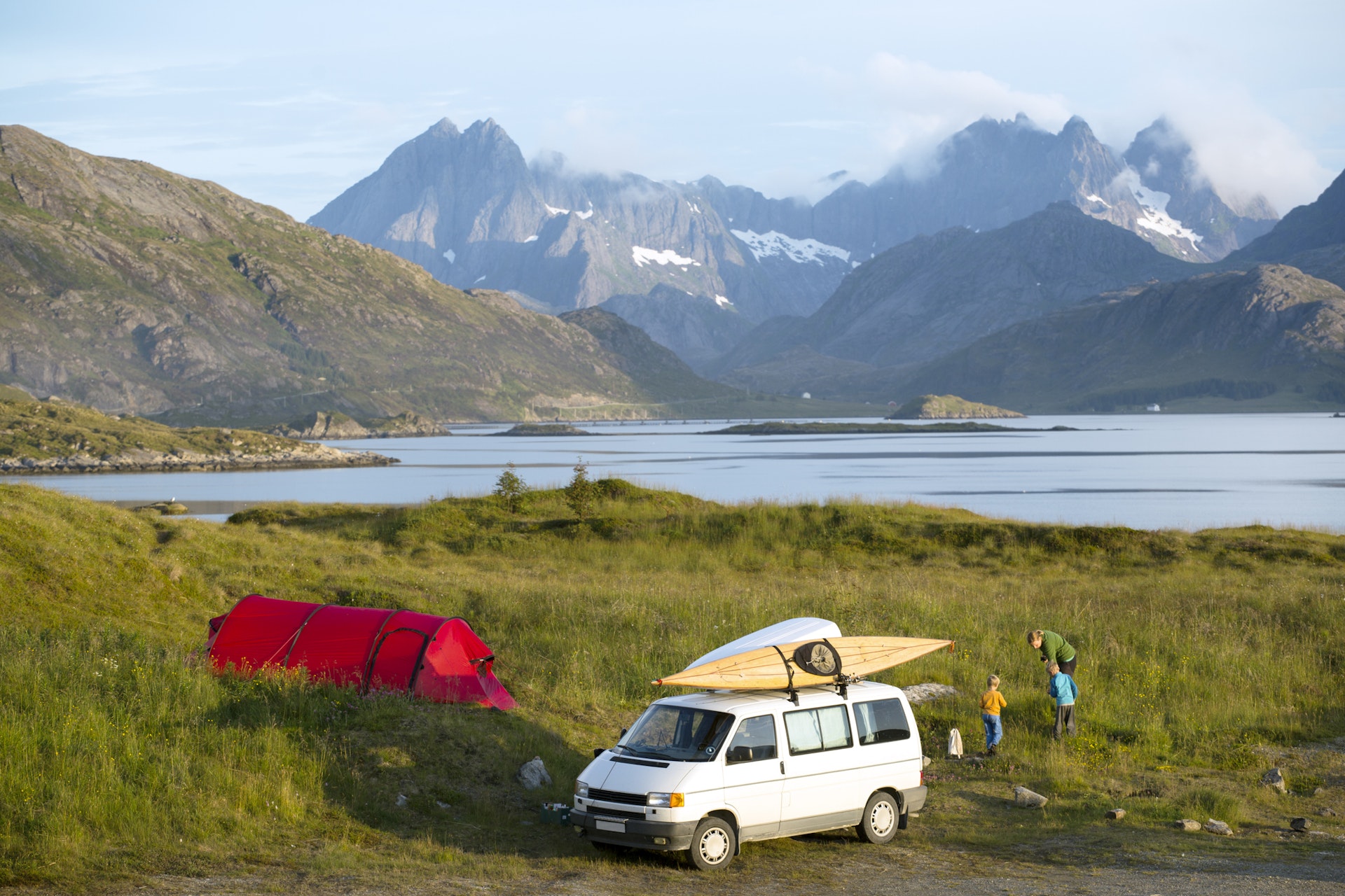 La Norvège à petit prix - Lonely Planet 9 Une famille à côté de son camping-car et de sa tente dans un parc en Norvège, avec des montagnes en arrière-plan.