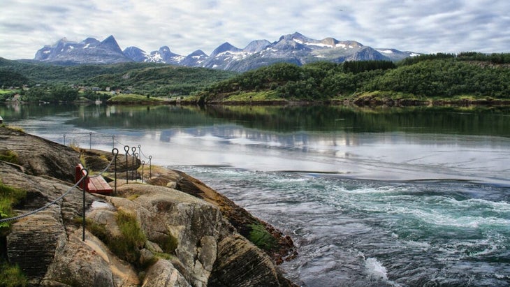 Voici les meilleures cabanes côtières de Norvège 23 Vue du fort courant du Saltstraumen, le plus puissant courant de marée au monde, avec un banc au premier plan et des montagnes à l'arrière-plan.