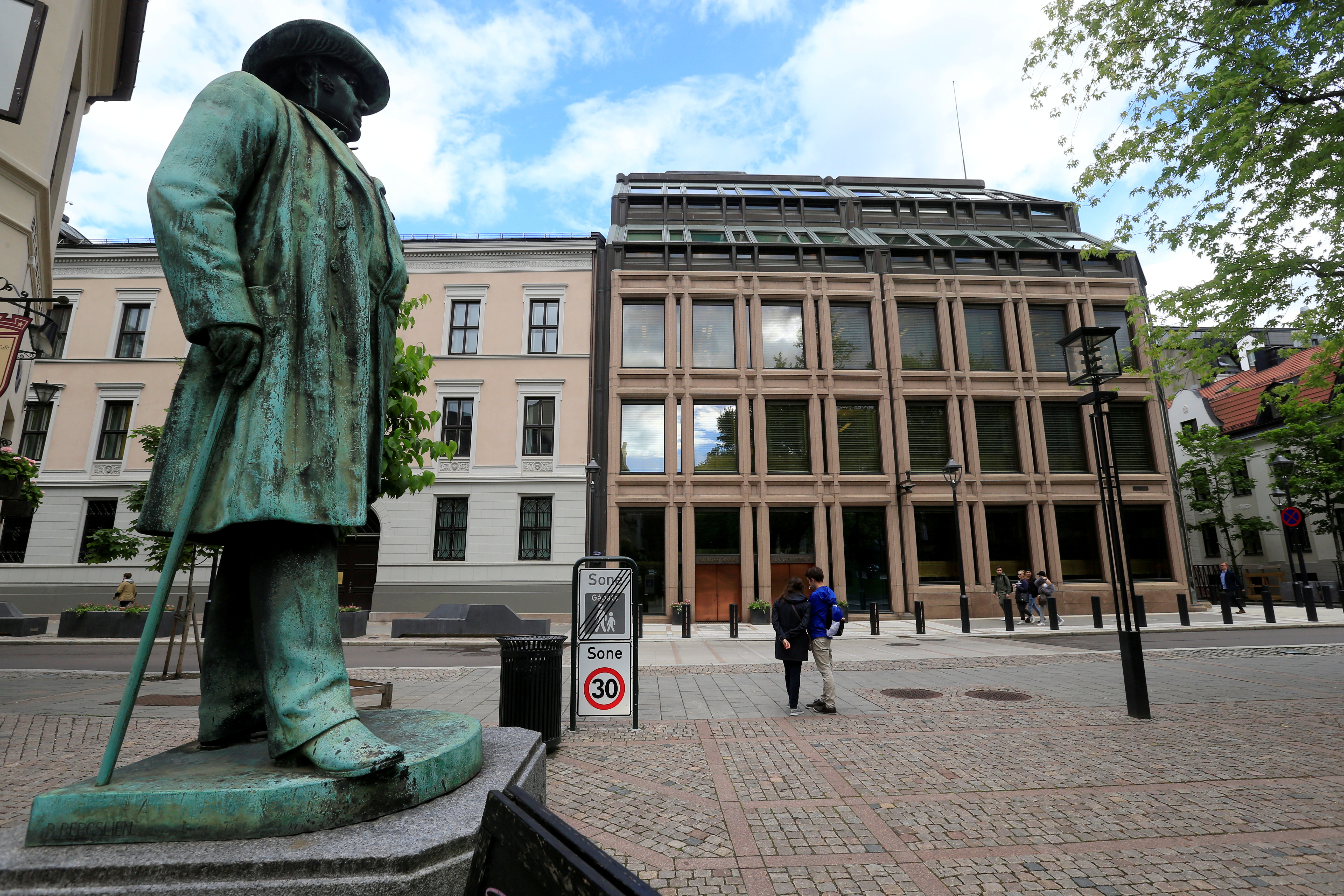 La banque centrale norvégienne relève son taux d'intérêt à 4,0 %, en vue d'une hausse en septembre 9 Des personnes vaquent à leurs occupations près du bâtiment de la banque centrale norvégienne à Oslo.