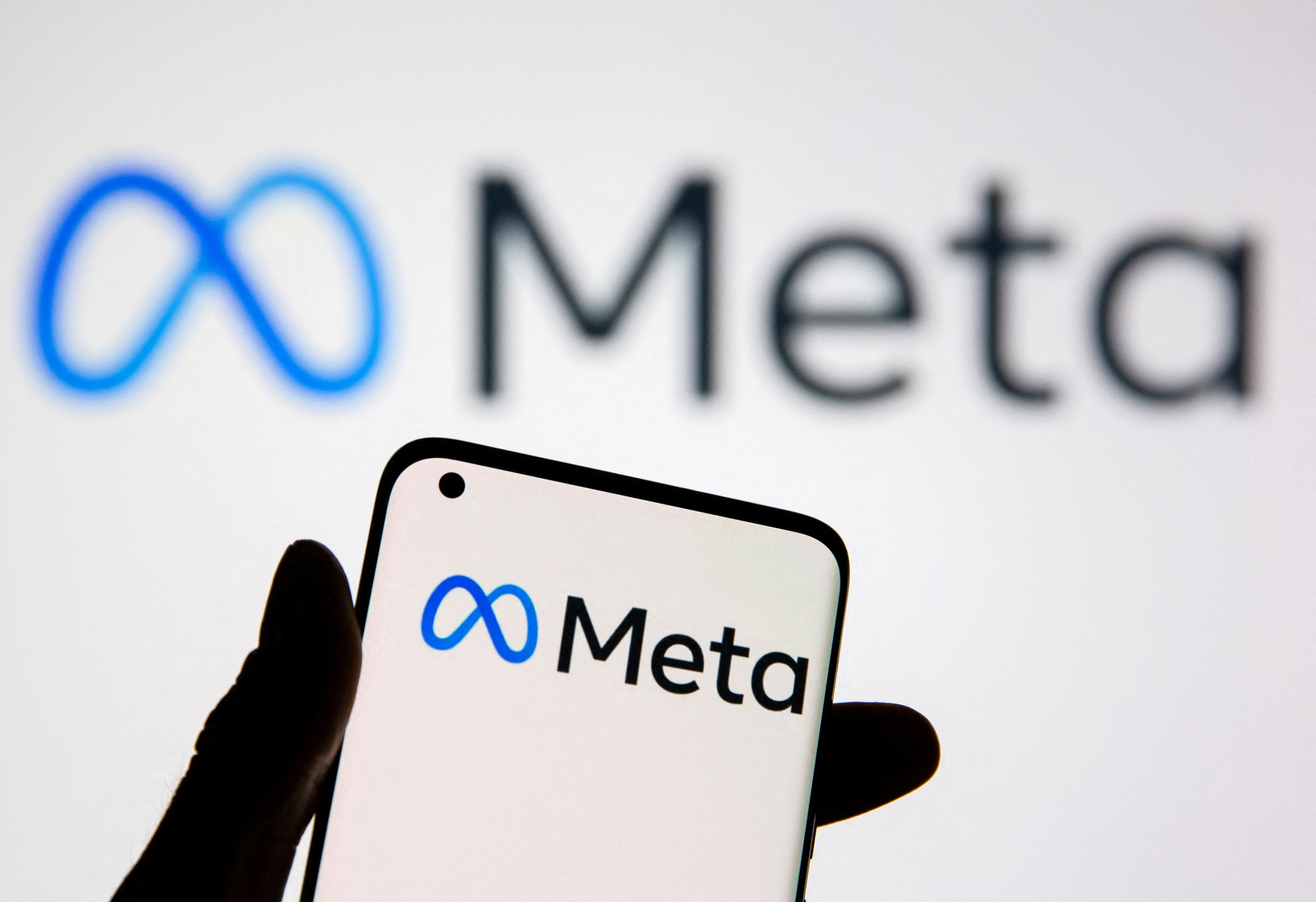 Un smartphone portant le logo Meta est vu devant le nouveau logo Meta de Facebook dans cette illustration.