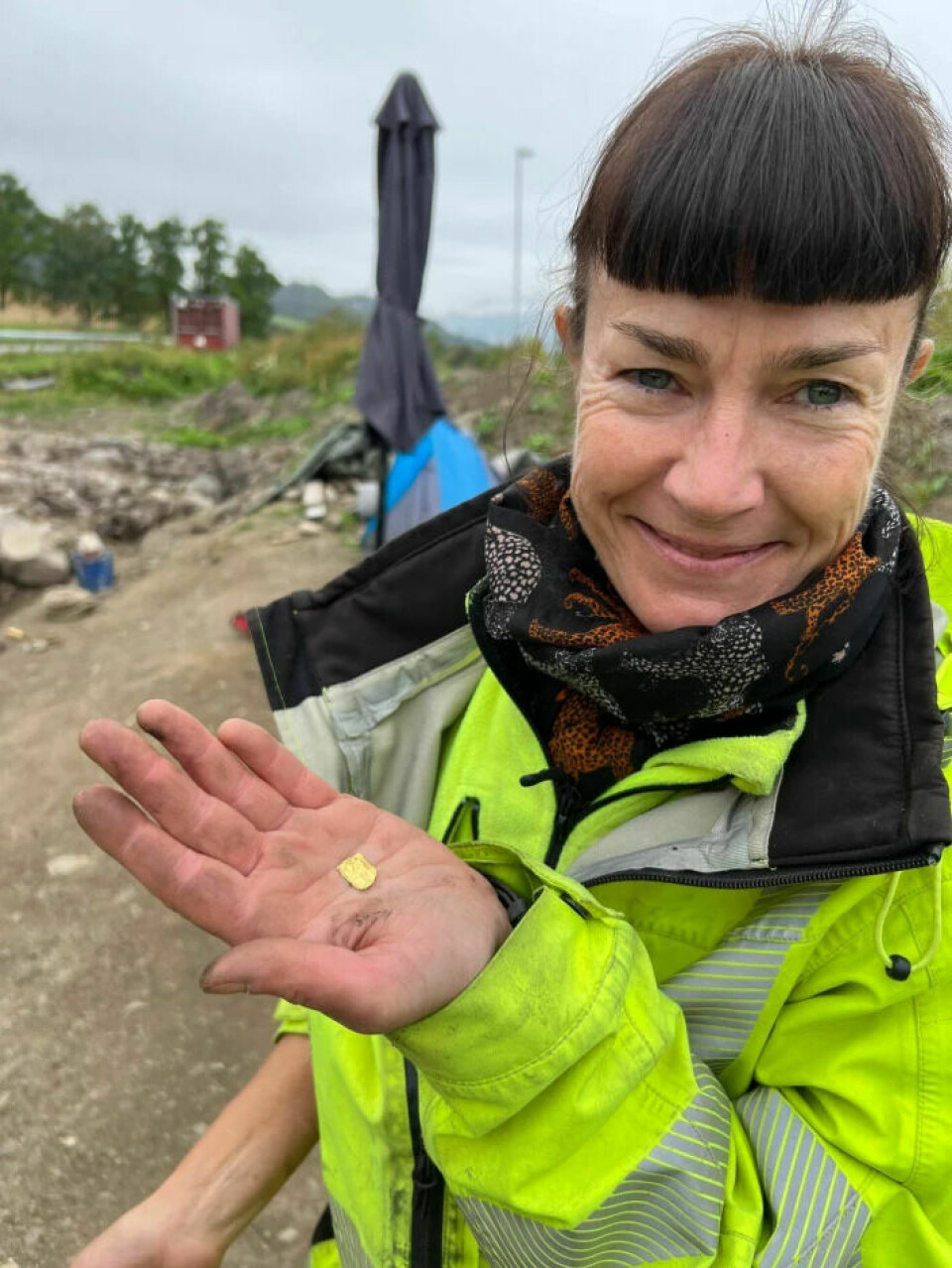 L'archéologue et chef de projet Kathrine Stene montre l'une des cinq nouvelles figurines en feuille d'or récemment découvertes à Hov, près de Lillehammer.