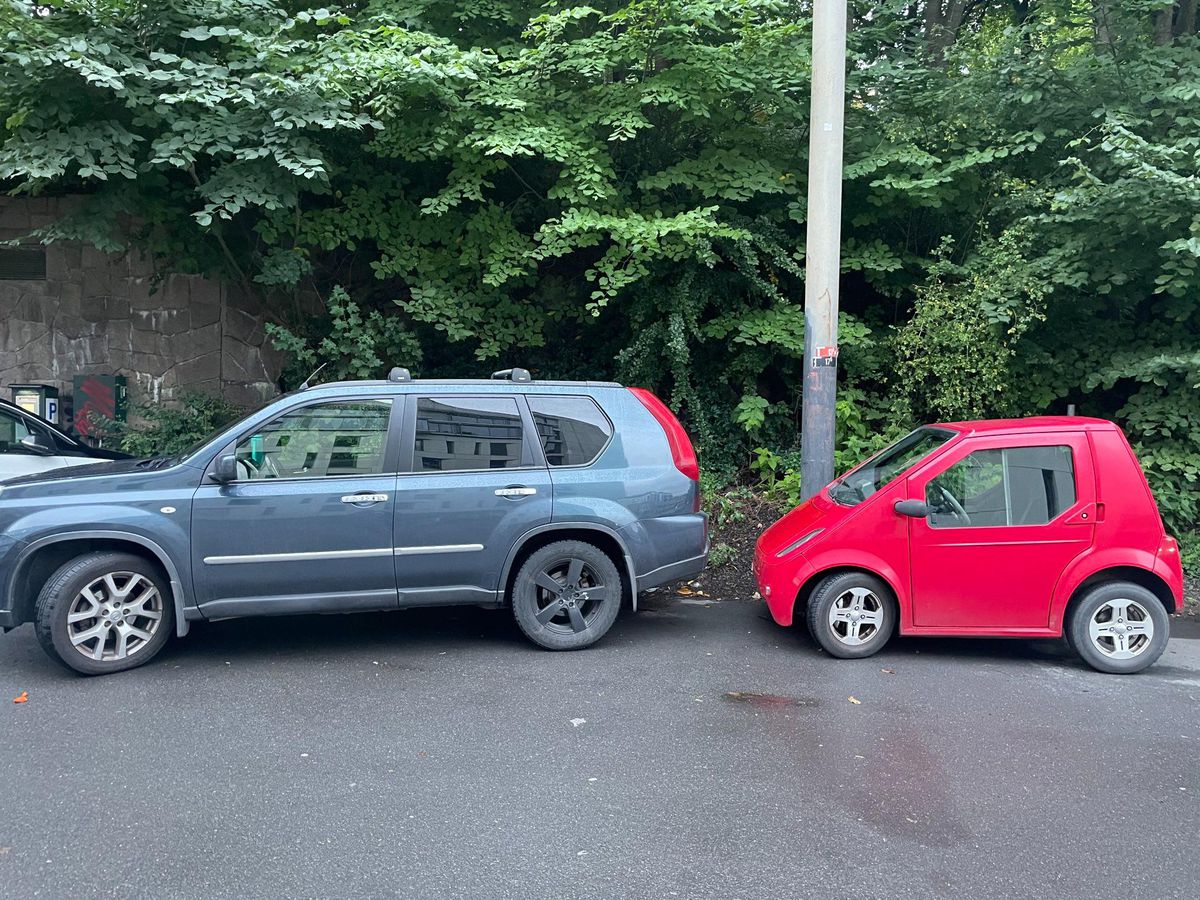 Pourquoi la Norvège repense-t-elle sa dépendance à l'égard des voitures électriques ? 13 Une petite voiture rouge à deux portes garée en parallèle avec un gros SUV devant.