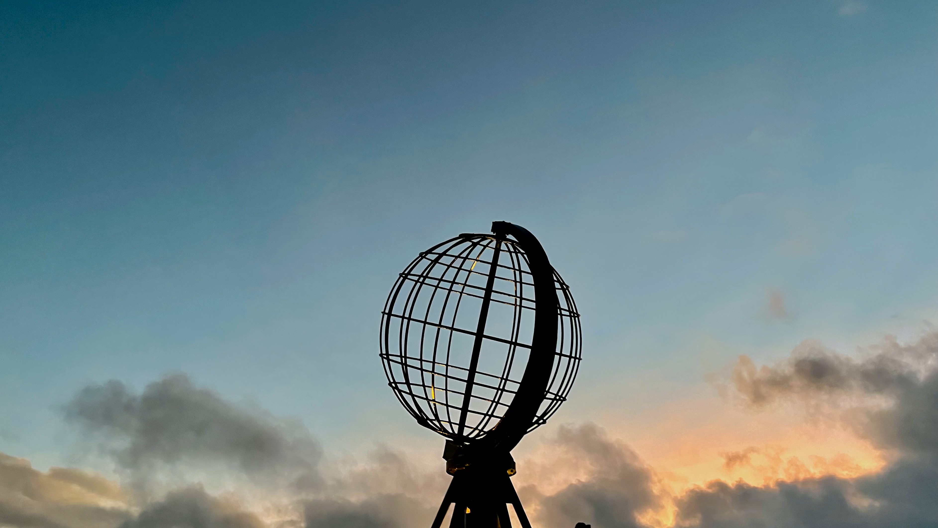 Monument du Cap Nord représentant un globe terrestre avec un ciel partiellement nuageux en arrière-plan.