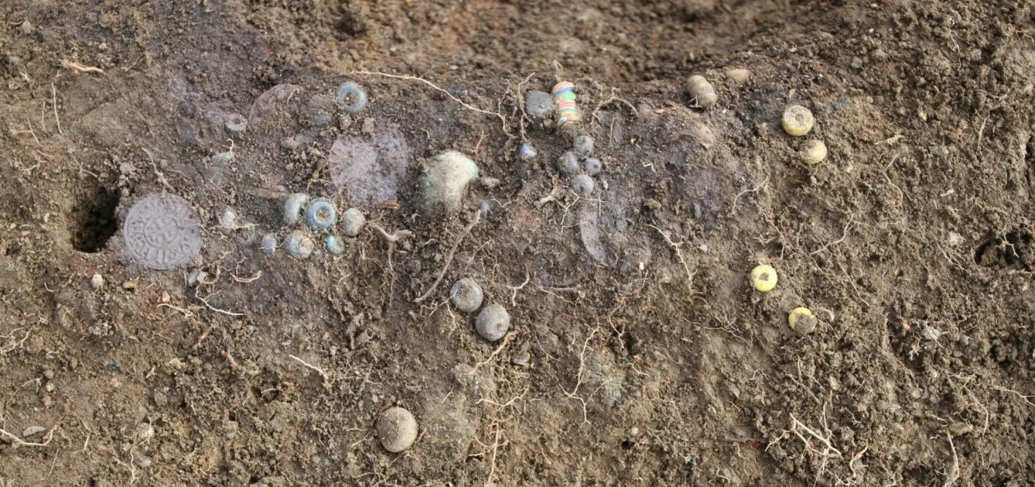Une « pierre de vulve » et des bijoux en pièces de monnaie parmi des trésors remarquables découverts sur un site funéraire viking en Norvège 21 Perles trouvées enfouies sur le site de fouilles.