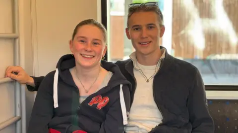 La Norvège appelle à l'action les jeunes qui quittent l'école et font la fête dans le bus de Russ, qui devient incontrôlable 34 Une adolescente et un adolescent sont assis ensemble et portent des hauts gris.