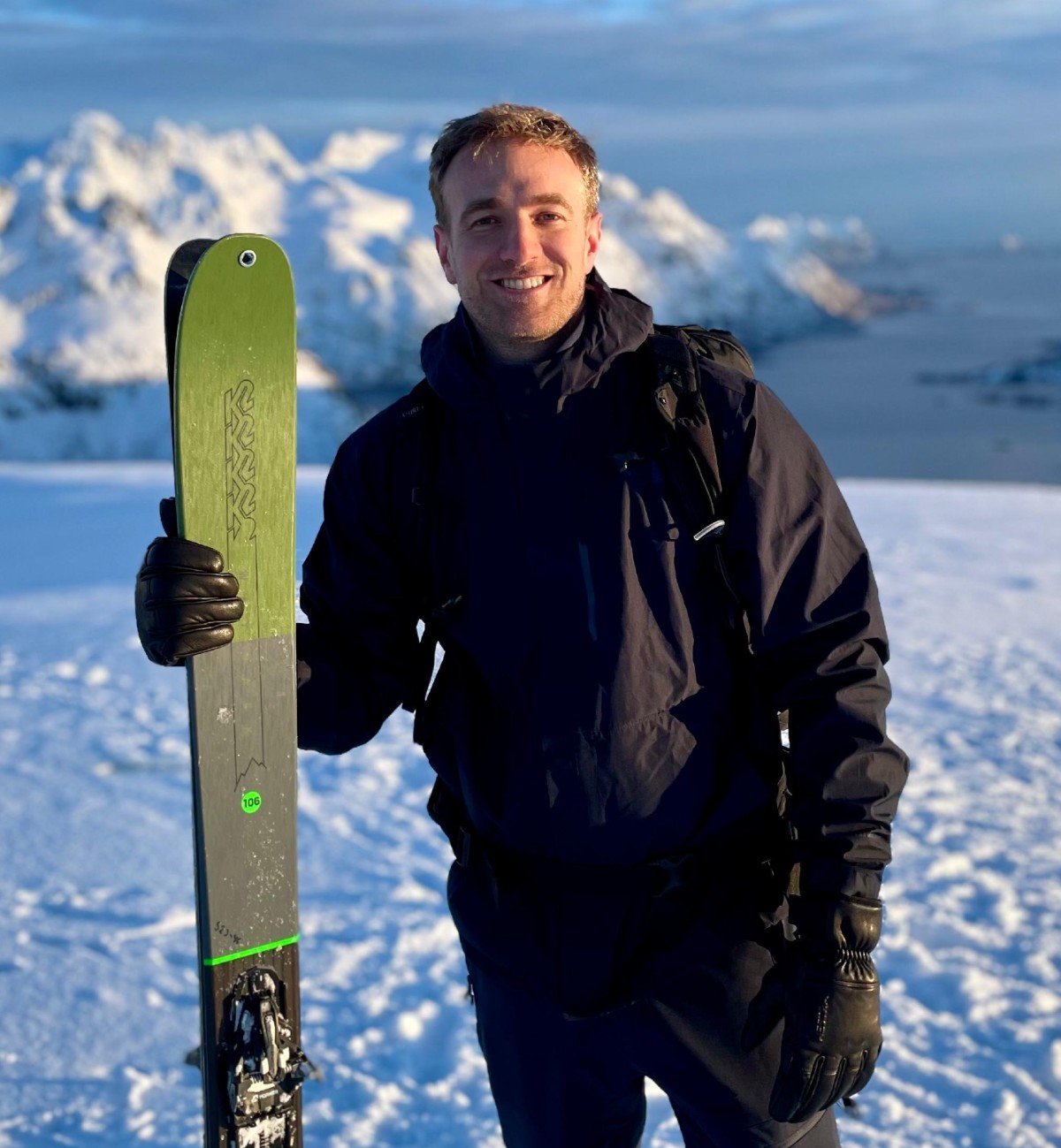 Cela vaut-il la peine d'apprendre le norvégien ? 9 Alistair Franke, de Londres, pose en tenant des skis sur une piste de ski enneigée avec des montagnes derrière lui.