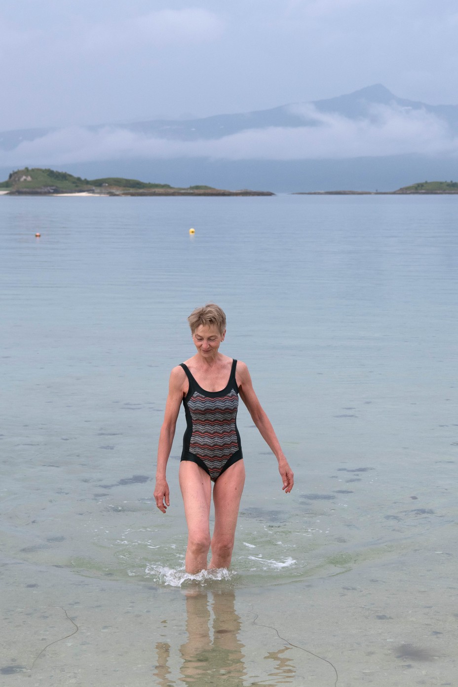 L'île sans temps - The Atlantic 32 Photographie couleur d'une femme marchant dans des eaux peu profondes en maillot de bain une pièce.