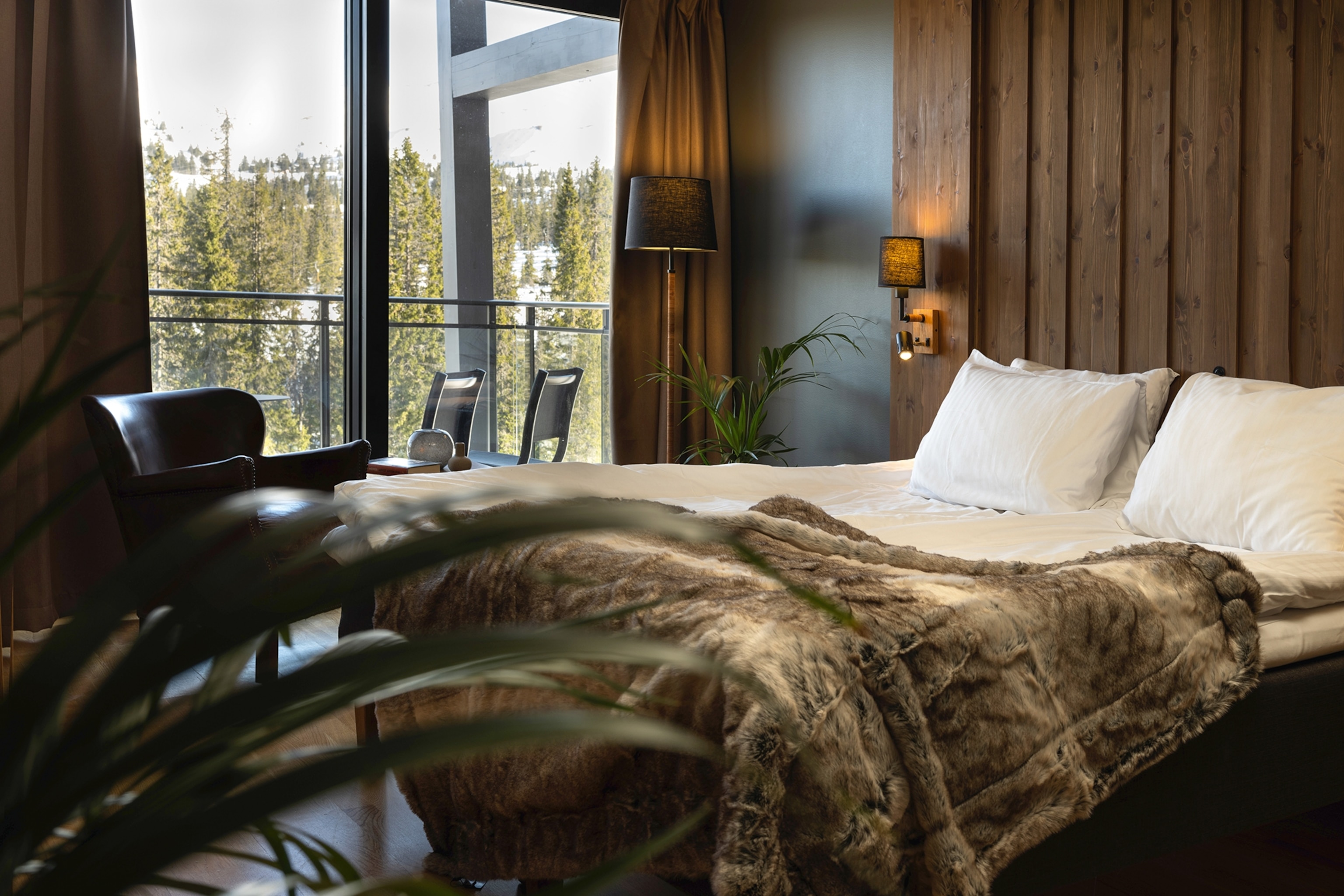 Pourquoi la Norvège et la Suède sont parfaites pour un séjour ski transfrontalier 7 L'intérieur d'un chalet de ski avec des panneaux en bois et un lit double recouvert d'une couverture en fourrure.