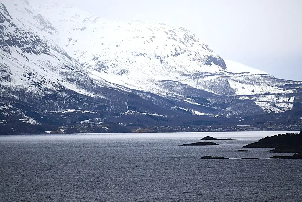 New Day Cafe - Photos de Suède et de Norvège 37 Vue sur un fjord norvégien vers une ville située dans les plaines de l'autre côté. Les montagnes enneigées s'élèvent abruptement depuis les plaines.
