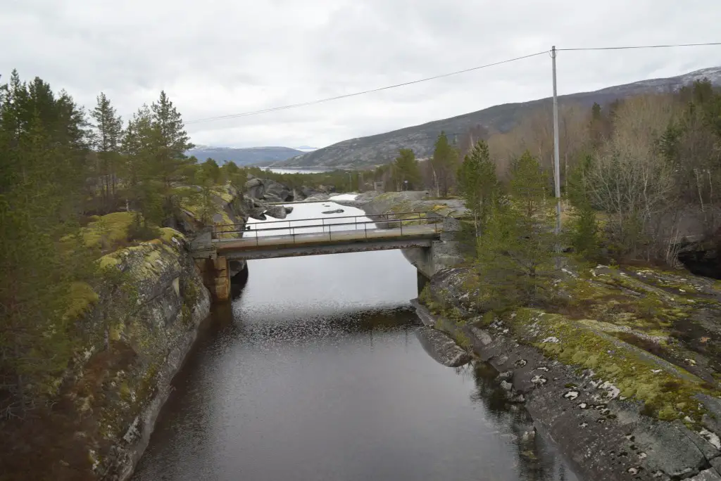 New Day Cafe - Photos de Suède et de Norvège 38 Un ruisseau enjambé par un pont, bordé de formations rocheuses moussues. Des forêts et des montagnes s'étendent de part et d'autre.