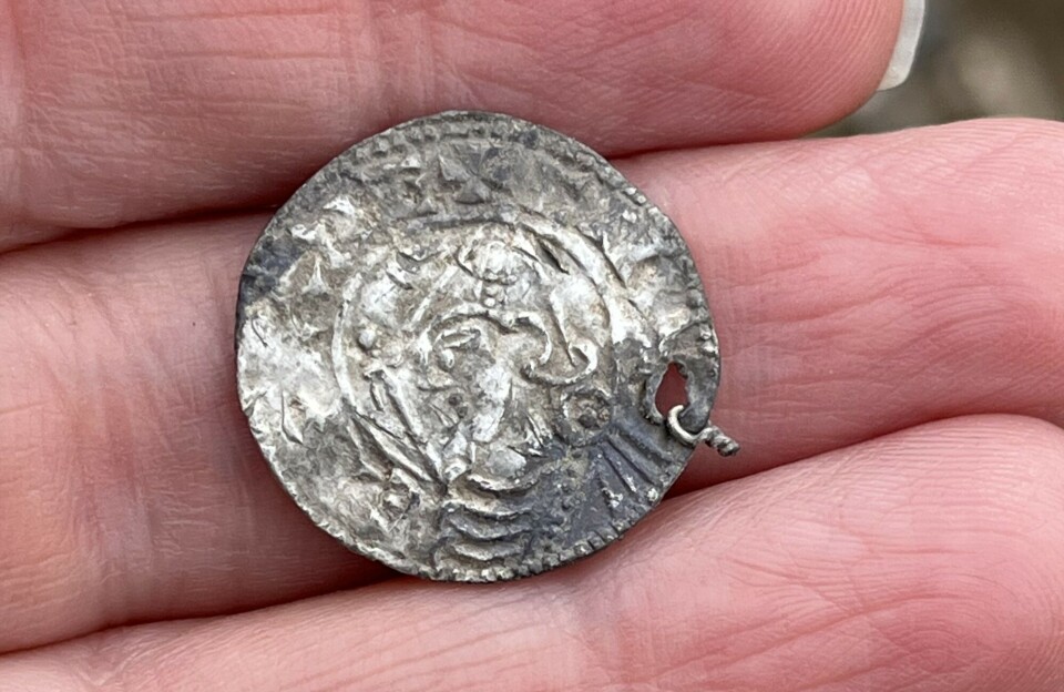 Découverte du plus grand trésor viking de Norvège, composé de 3 000 pièces d'argent : « Vraiment exceptionnel » 28 Gros plan d'une pièce d'argent patinée posée sur le bout des doigts d'une personne à l'extérieur.