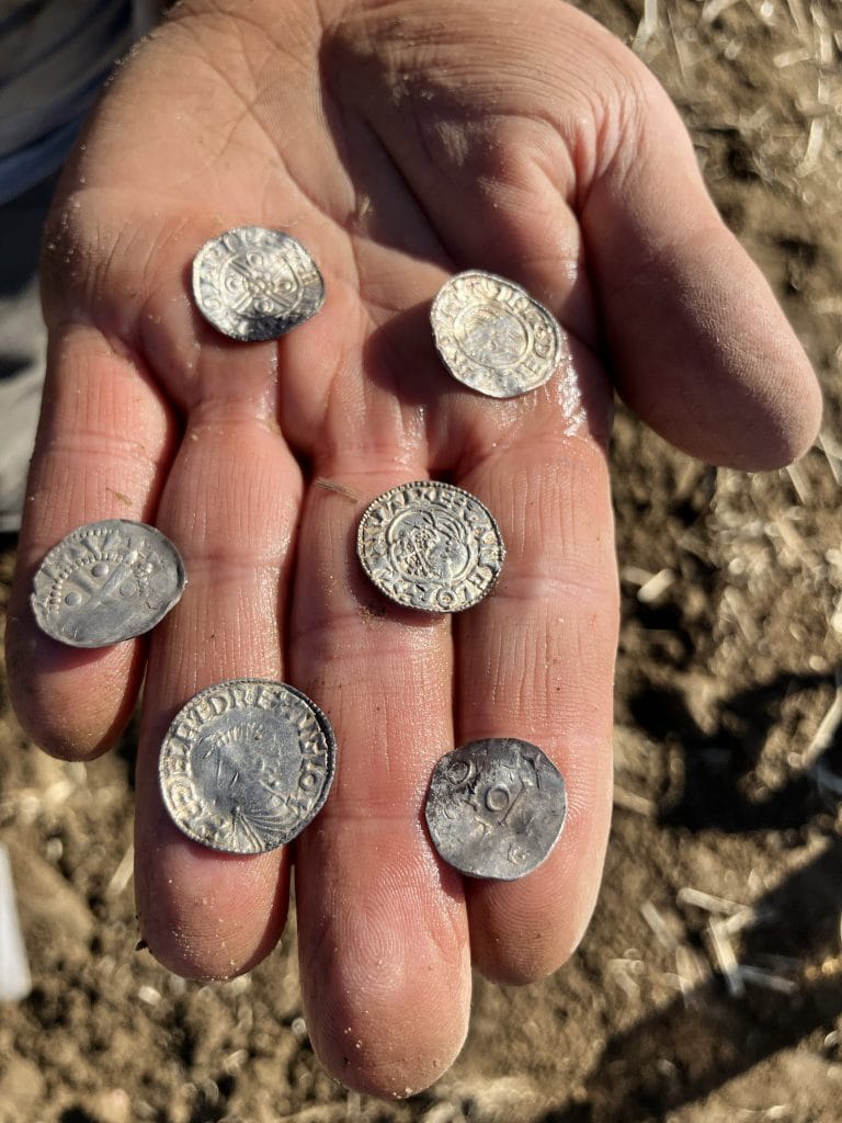 Des amateurs de détecteurs de métaux mettent au jour le plus grand trésor de pièces vikings jamais découvert en Norvège 9 Une main tenant six pièces anciennes anglaises et allemandes